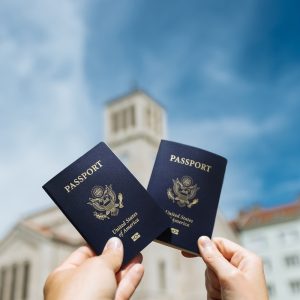 two people holding up two passports in front of a building